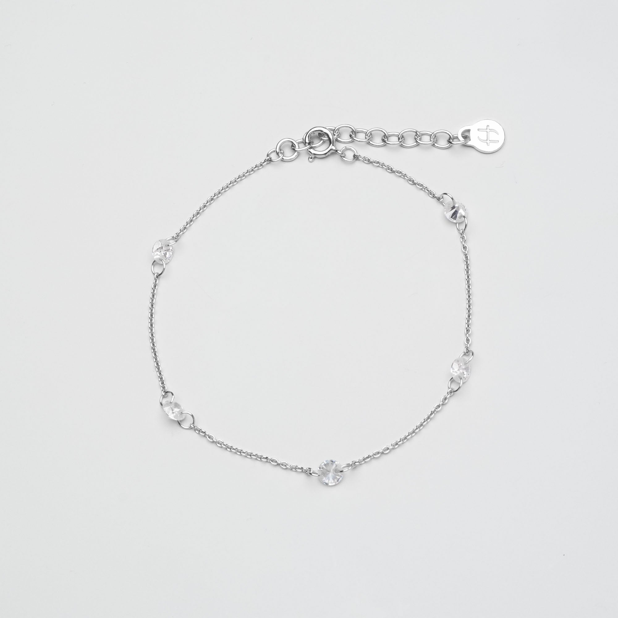 Zartes silbernes Gliederkette-Armband mit fünf eingearbeiteten, rund gefassten Zirkonia-Steinen vor hellem Hintergrund.