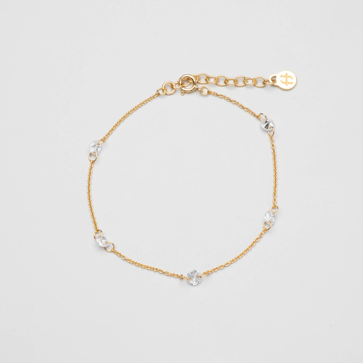Zartes goldenes Gliederkette-Armband mit fünf eingearbeiteten, rund gefassten Zirkonia-Steinen vor hellem Hintergrund.