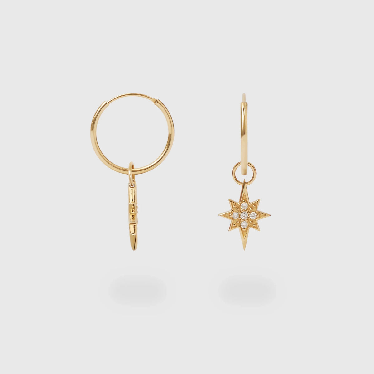 Goldener Creolen-Anhänger in Sternform, besetzt mit funkelnden laborgezüchteten Diamanten, abgebildet neben einer passenden Goldcreole vor hellem Hintergrund.