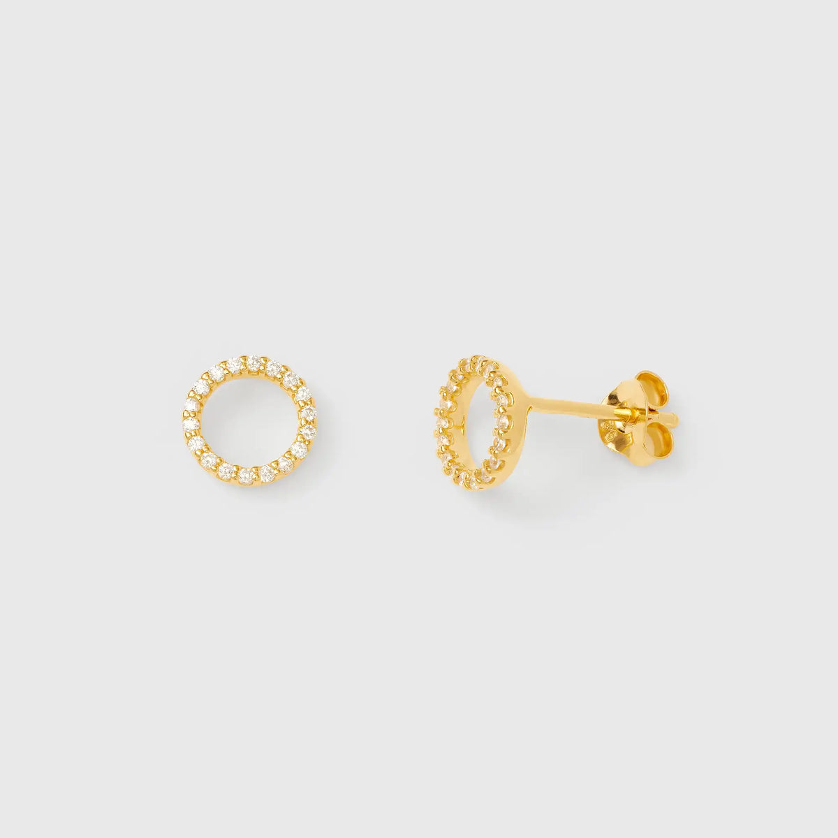 Goldener offener Kreis-Ohrstecker mit dicht besetzten Zirkonia-Steinen in Pavé-Fassung vor hellem Hintergrund