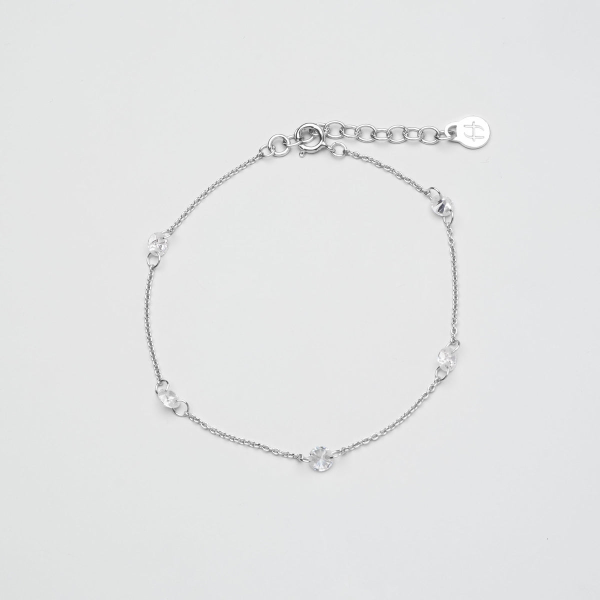 Zartes silbernes Gliederkette-Armband mit fünf eingearbeiteten, rund gefassten Zirkonia-Steinen vor hellem Hintergrund.