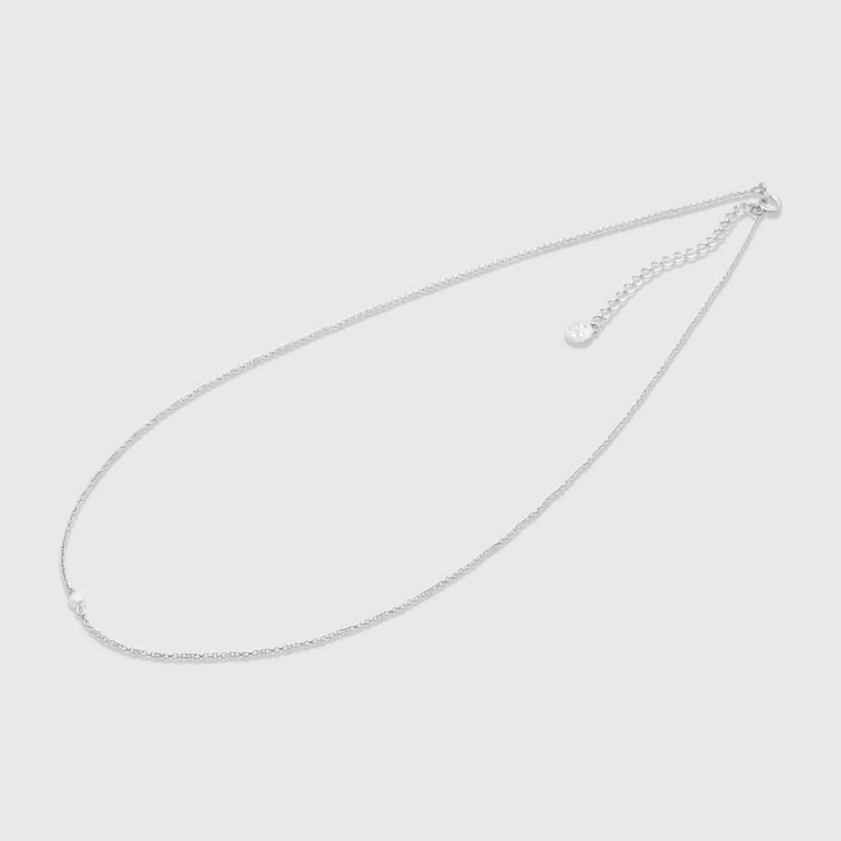 Feine silberne Halskette mit einer zentrierten, einzelnen Süßwasserperle als minimalistischem Anhänger vor hellem Hintergrund.