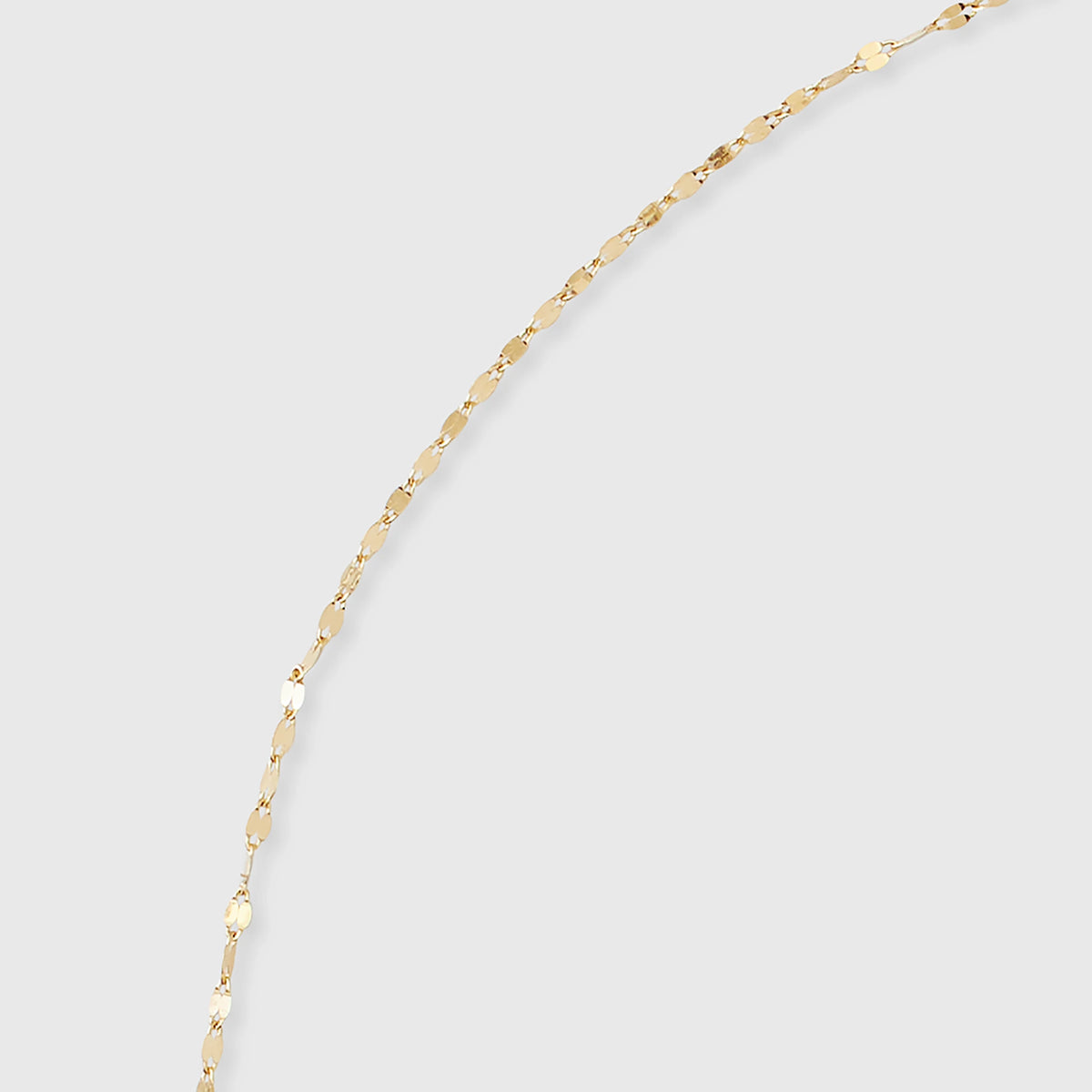 Nahaufnahme einer filigranen Ankerkette aus glänzendem Echtgold mit flach geprägten Kettengliedern vor hellem Hintergrund.