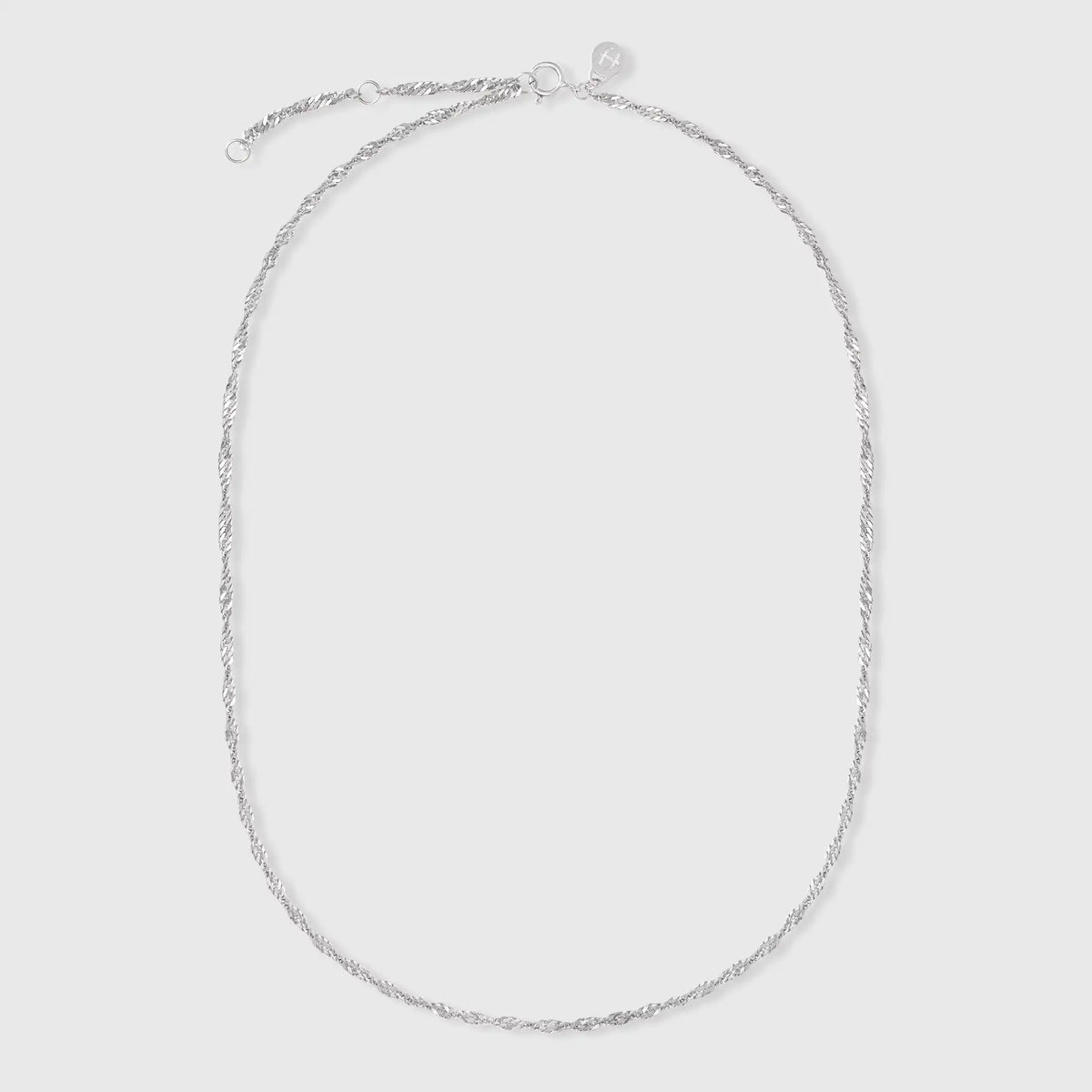 Filigrane gedrehte Gliederkette in Silber mit fejn Logo-Plättchen vor hellem Hintergrund