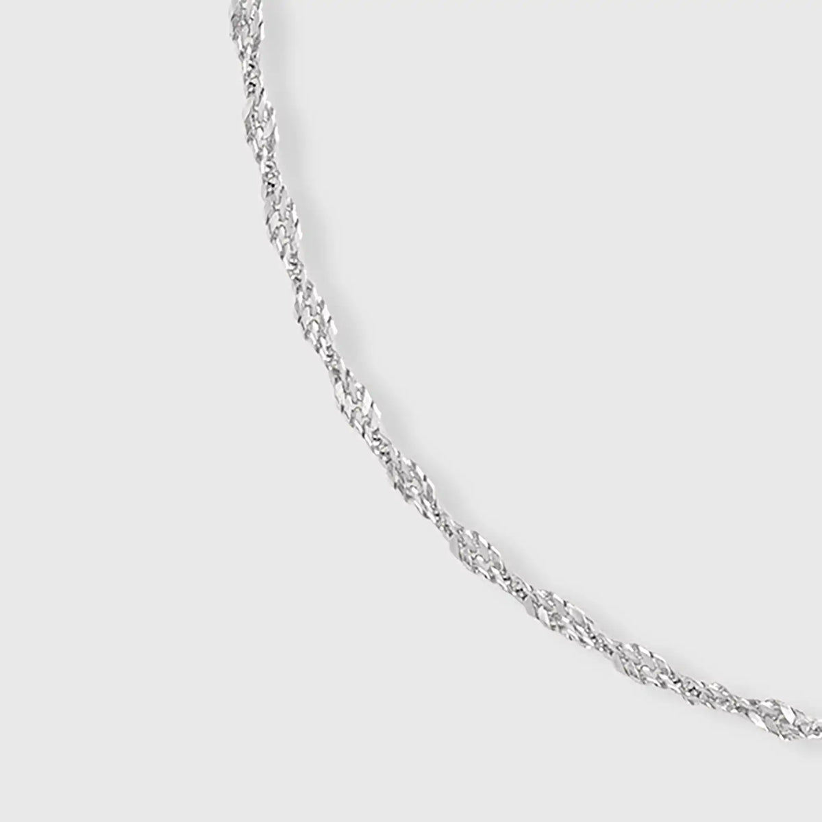 Detailaufnahme: Filigrane gedrehte Gliederkette in Silber mit fejn Logo-Plättchen vor hellem Hintergrund