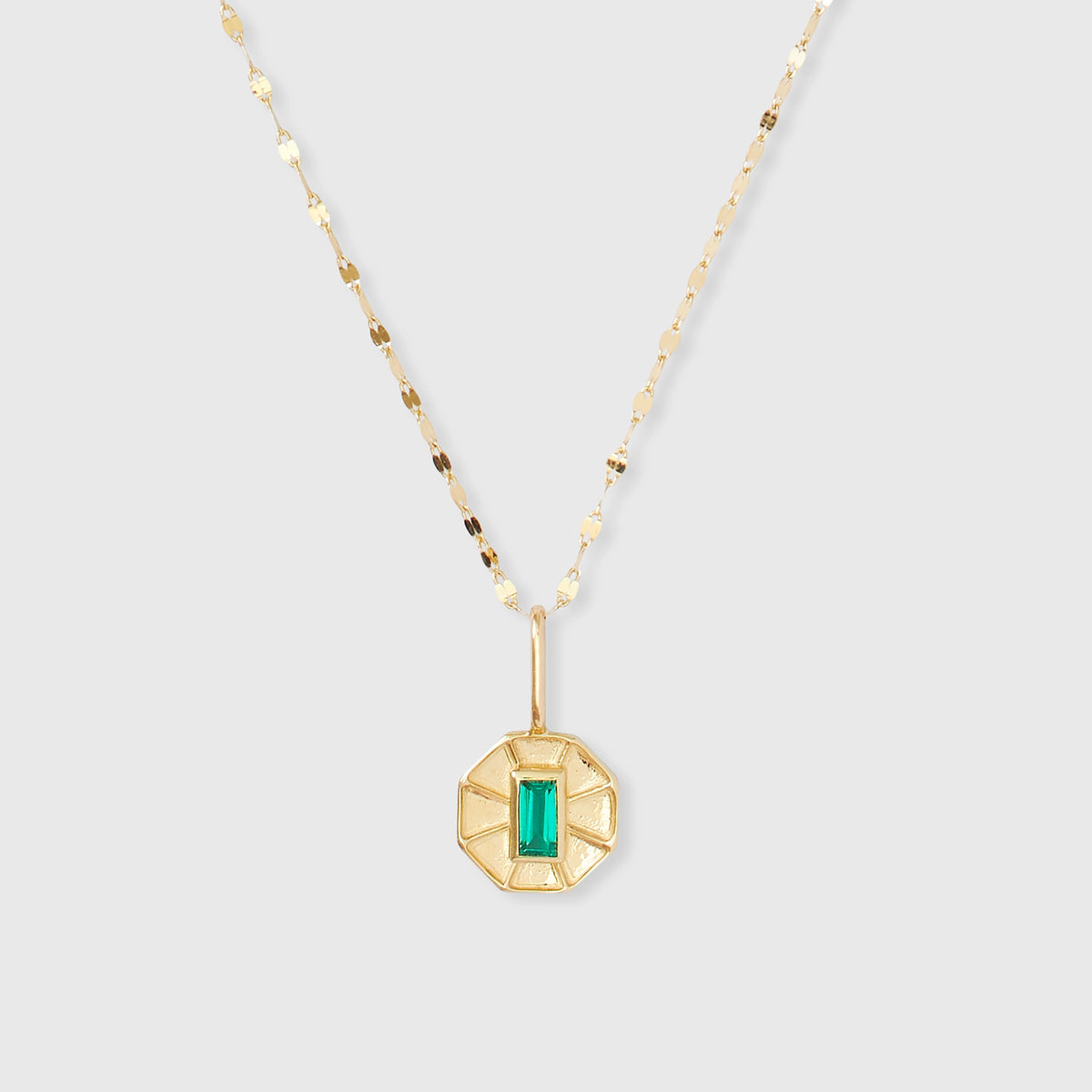 Achteckiger Kettenanhänger aus glänzendem Echtgold mit einem rechteckigen, grün leuchtenden Edelstein im Art-Déco-Stil an einer filigranen Goldkette.